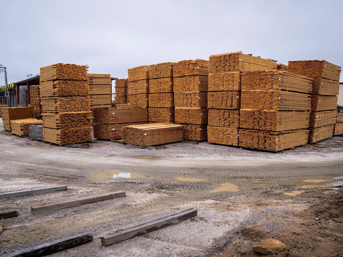 Contractor examining a stack of surplus lumber and palletized material at a jobsite